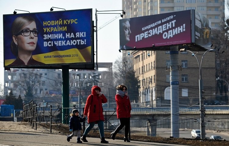 People walking near political billboards of Ukrainian candidates of presidential election, Kyiv.