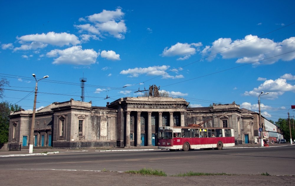 Old soviet red trolleybus with abandoned building of cinema "Metallurg". Soviet stalin architecture. Alchevsk, Luhansk region, Ukraine. Source: Shutterstock