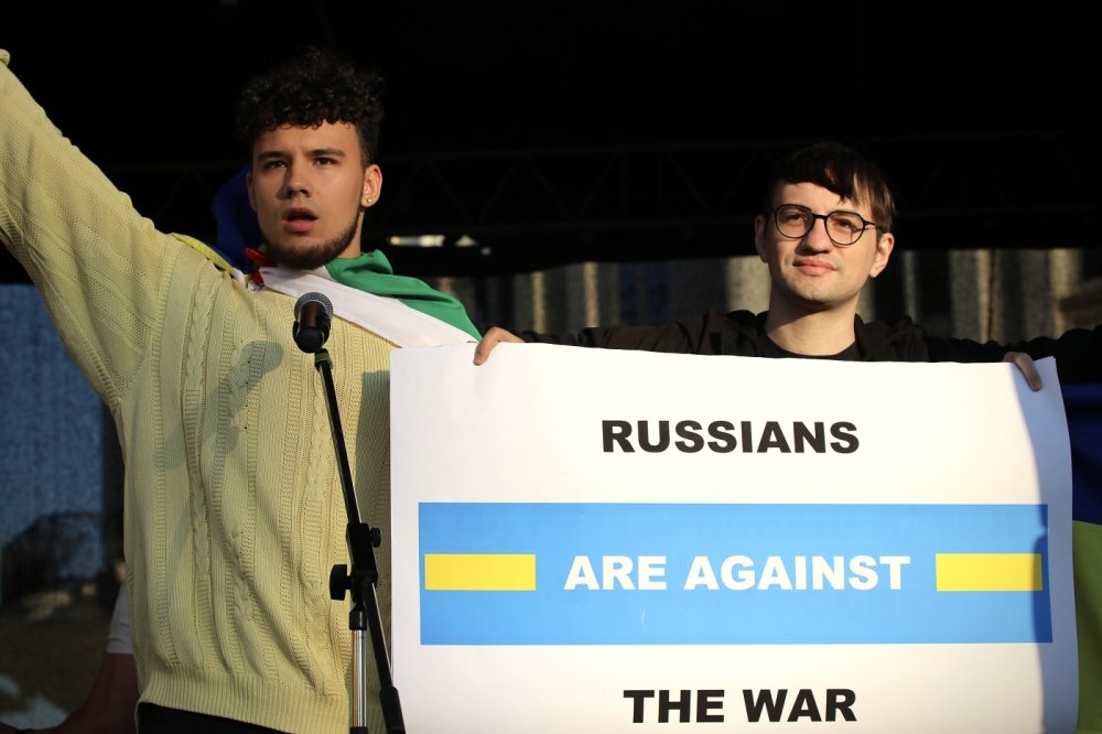 two protestors hold up a sign reading "Russians are against the war"