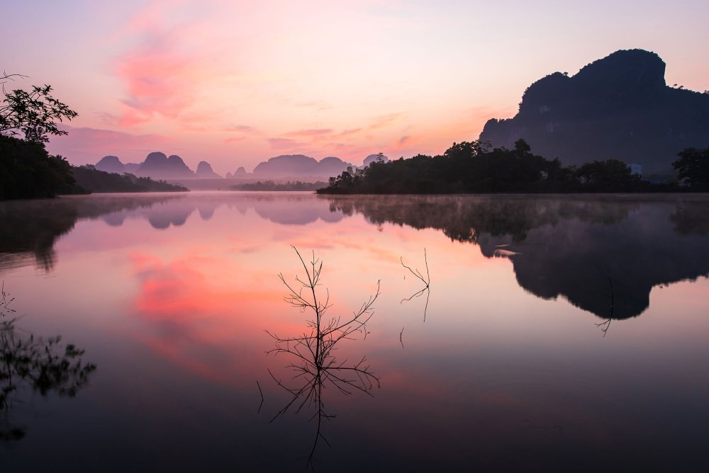 A sunset over a lake with mountains in the background.