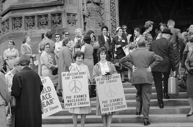 Women on steps holding signs "No Nuclear Arms for Canada