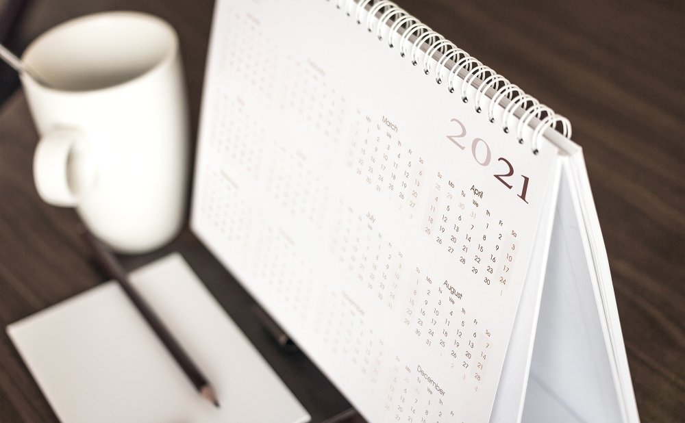 A coffee mug sits next to a desk calendar that shows the year 2021