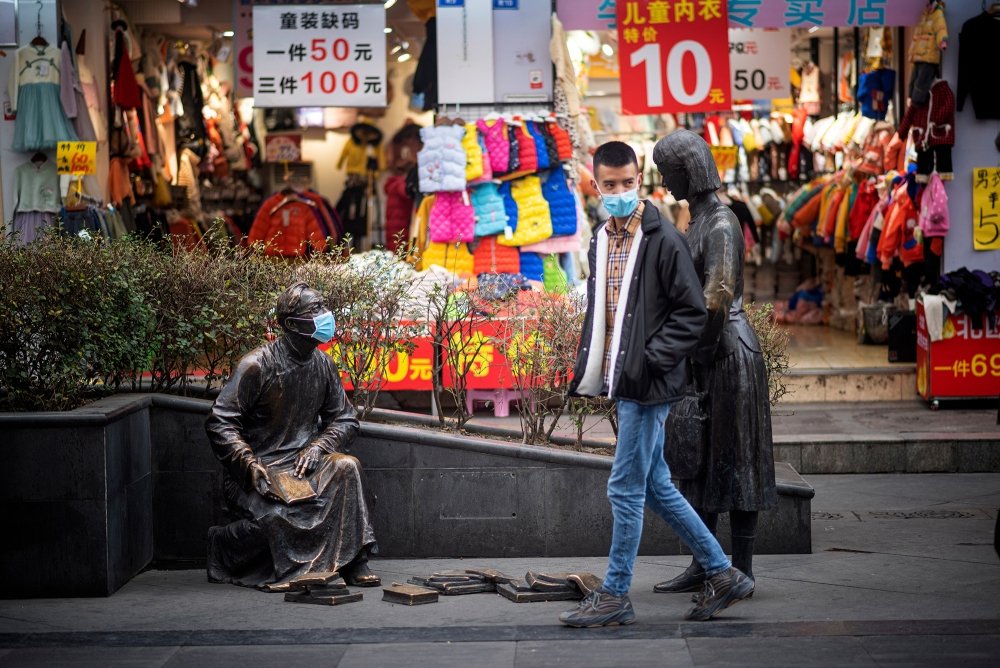 A person and a statue both wear masks on the street to prevent infection from coronovirus during the Chinese New Year in Chengdu, China.