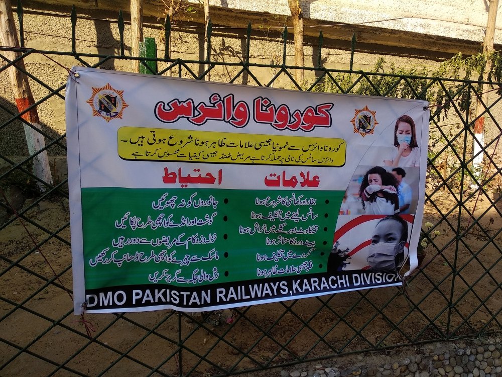 A banner in Urdu language describing the symptoms and precautions for Corona Virus at City railway Station - Karachi, Pakistan. 