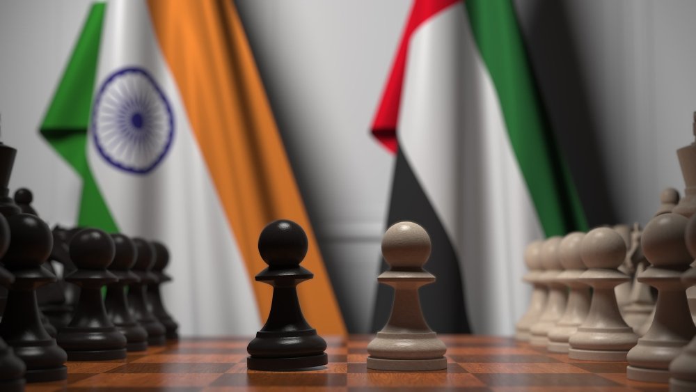 Flags of India and UAE behind pawns on the chessboard.