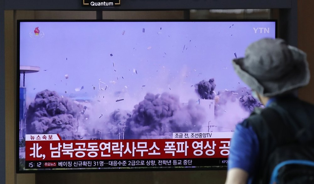 A man watching a TV screen showing a news program with a video of the demolition of the inter-Korean liaison office building in Kaesong, North Korea.