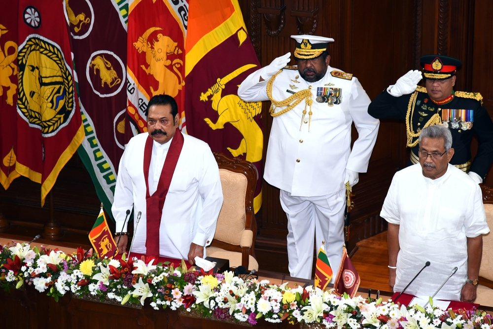 Prime Minister Mahinda Rajapaksa and President Gotabaya Rajapaksa stand in front of two soldiers at a swearing in ceremony