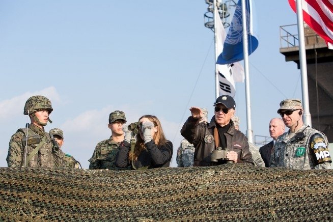 Vice President Biden stands with a group of soldiers at a barricade.