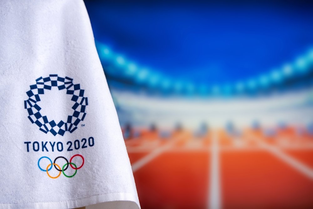 A towel with the logo for the Tokyo 2020 olympics in the foreground with track and field starting blocks in the background in soft focus