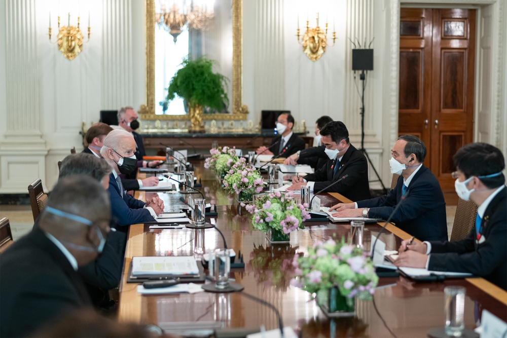 A group of men including President Biden and PM Suga sit around a conference table
