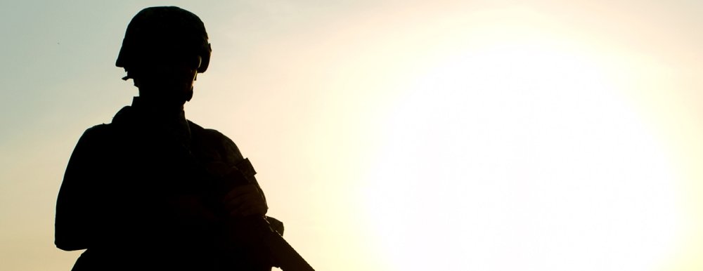 A soldier is silhouetted against a sunset