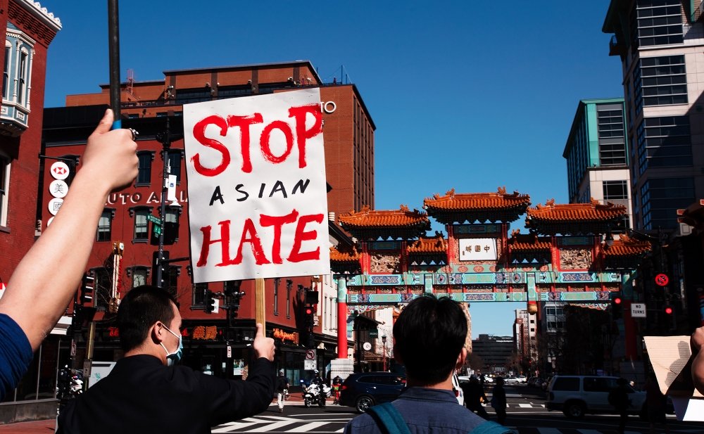 People march in the streets of Chinatown, one holding a sign that reads Stop Asian Hate