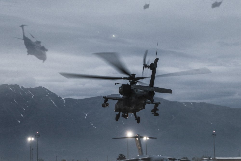 An image of an AH-64 helicopter in Aghanistan with another image superimposed on top showing CH-53 helicopters in Vietnam