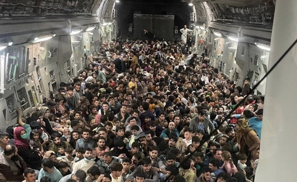 Hundreds of Afghan citizens crowd across the floor of an American military airplane.