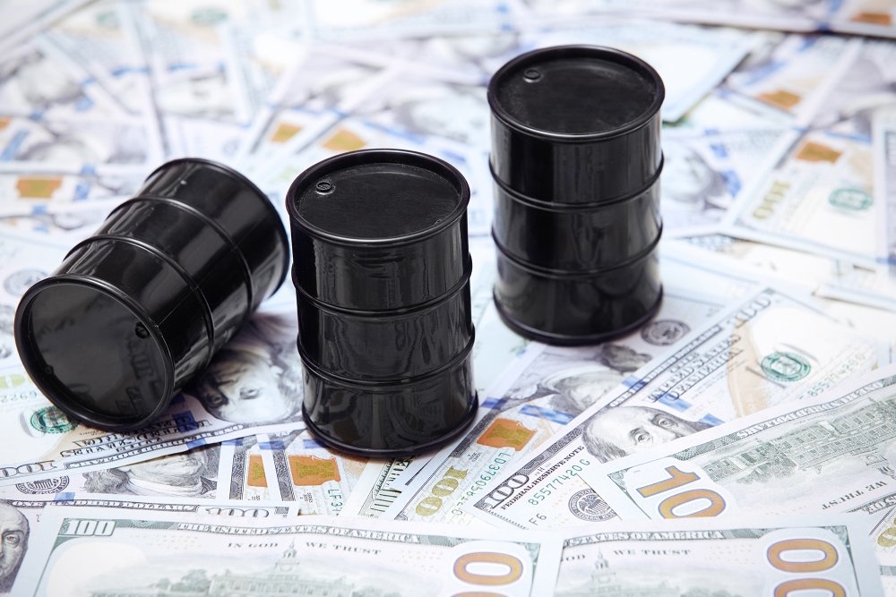 A picture of three oil barrels on a stack of U.S. currency