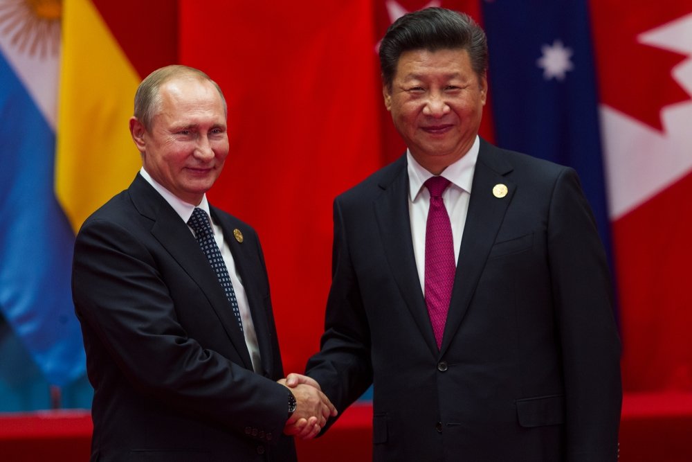 A picture of Xi Jinping and Vladimir Putin shaking hands.