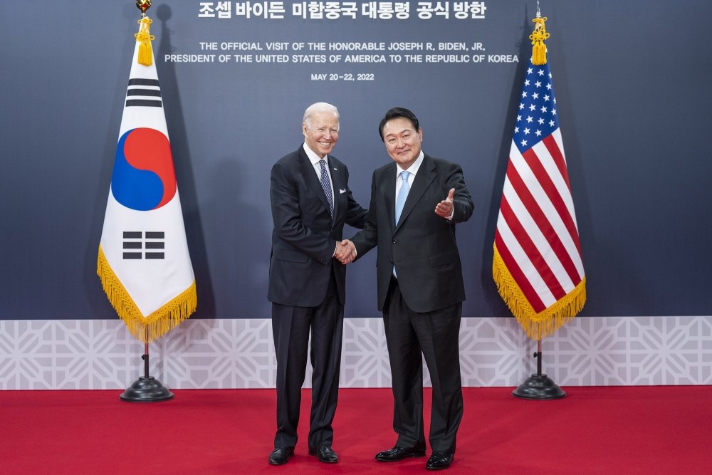 President Biden and President Yoon shaking hands in front of a banner announcing the official visit in 2022.