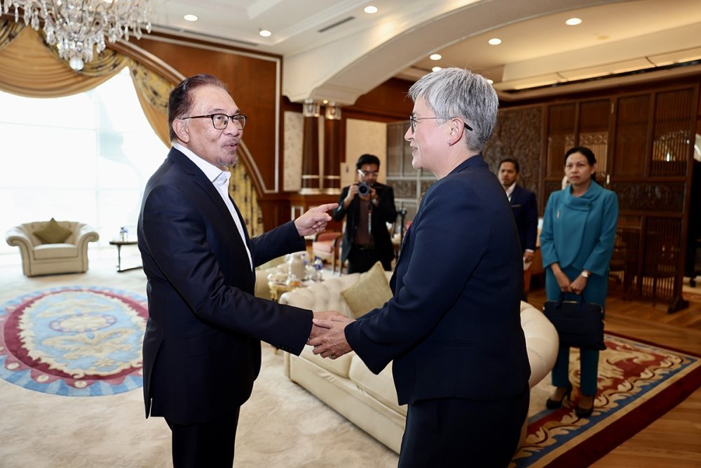 Anwar Ibrahim shakes hands with Penny Wong in an ornate office.