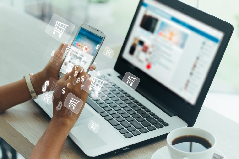 Businesswoman using laptop and phone with digital icon overlays.