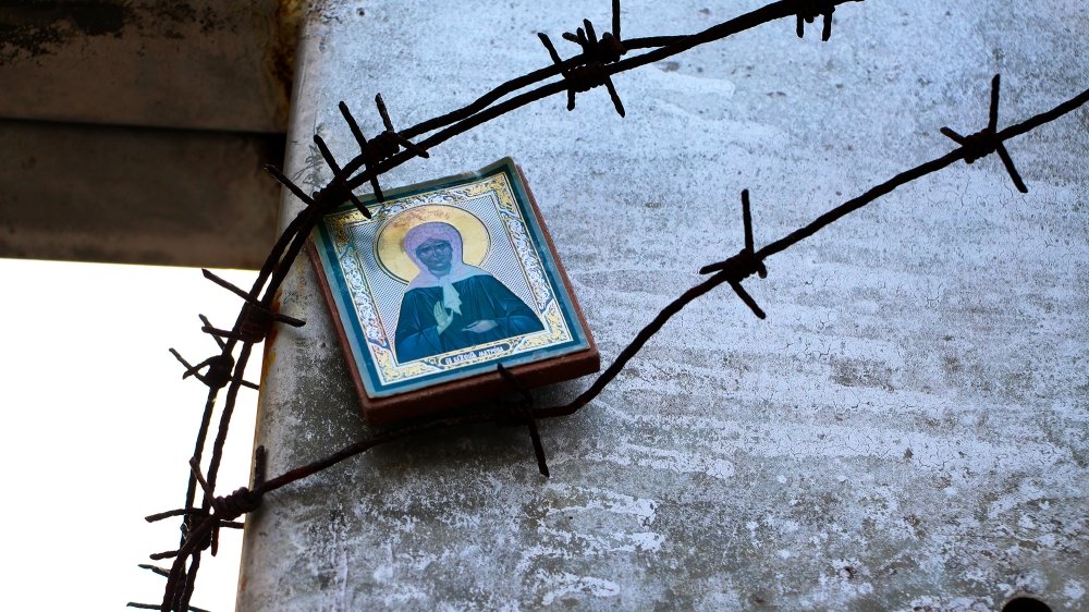 The icon of the Holy Mother is fixed under the barbed wire on the memorial cross to the victims of the Gulag. Stalinist repression. 