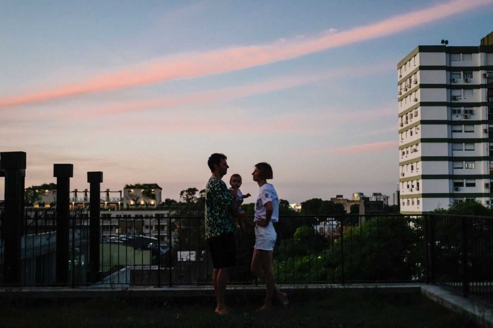 Husband, wife, and baby on balcony overlooking city 