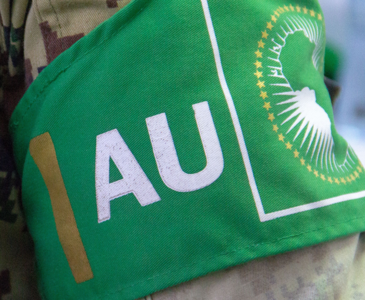 A soldier from the African Union Mission in Somalia (AMISOM), wears a green armband over his camouflage uniform reading AU (African Union), and with the AU flag.