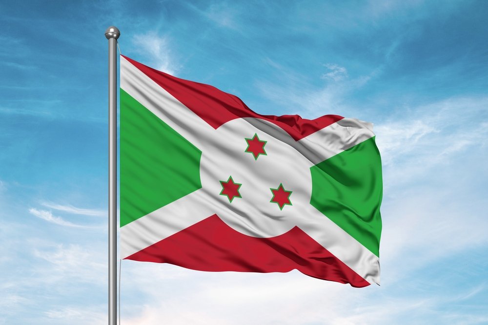 Burundi national flag cloth fabric waving on beautiful sky.