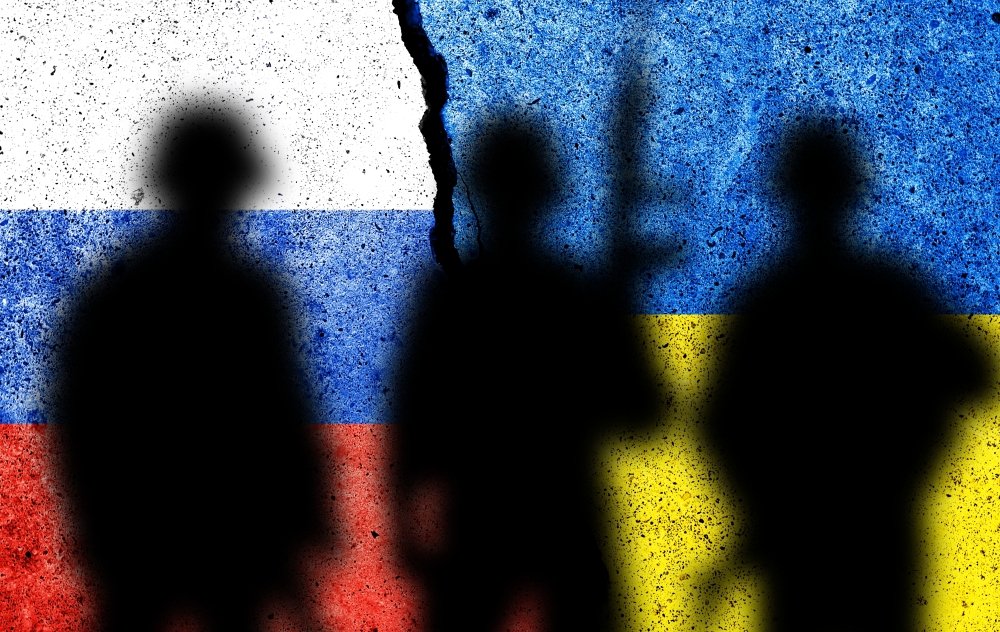 soldier silhouettes stand before Russian and Ukrainian flags