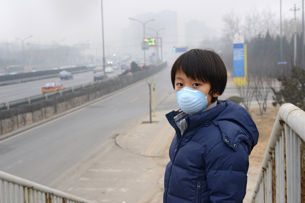 A boy standing with smog in the background,