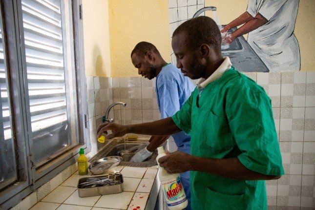 two doctors in healthcare facility cleaning utensils and washing hands