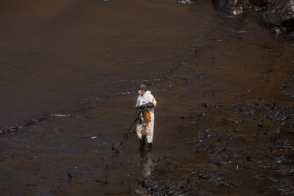 Callao, Peru; January 19, 2022: Workers clean after an oil spill, on Cavero Beach in the Ventanilla district of Callao. From La Pampilla Repsol refinery