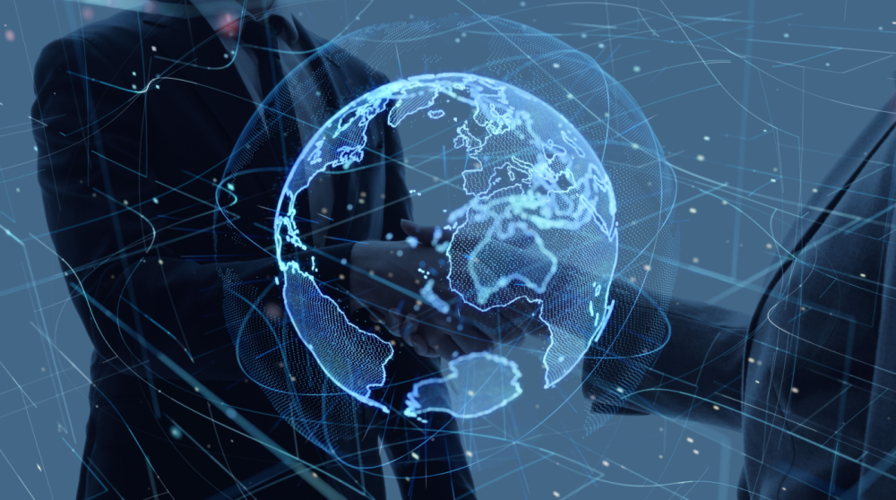 Two people shaking hands behind an image of the world
