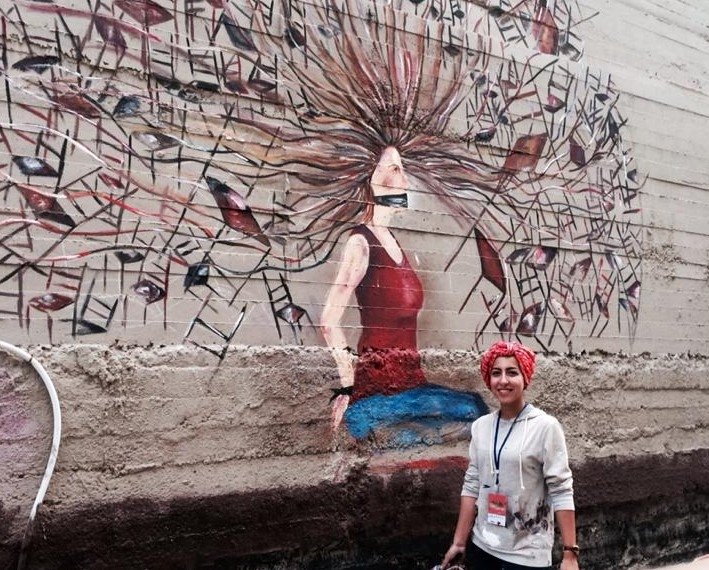 Street Artist Nour Qussini with her artistic piece at the WOW Baladak Street Art Festival in Amman, Jordan: Women on Walls: From Fear to Freedom, 2014.