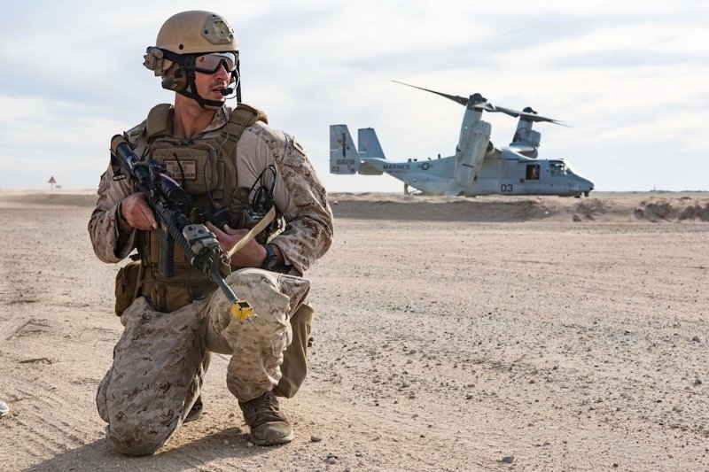 U.S. soldier crouches in front of aircraft