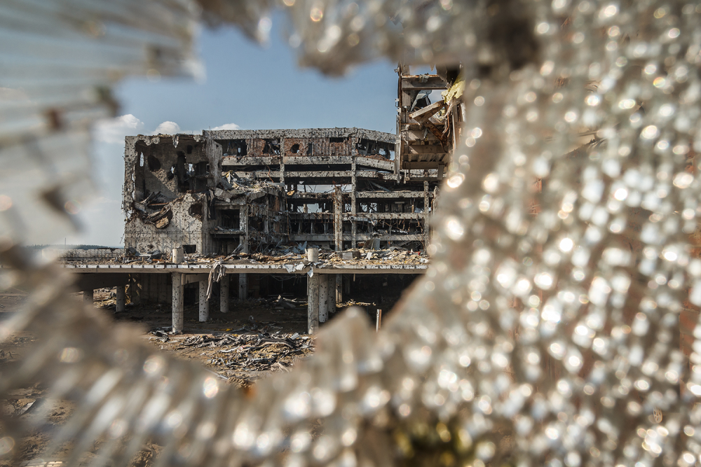 Wide angle view of Donetsk airport ruins through broken glass after massive artillery shelling.