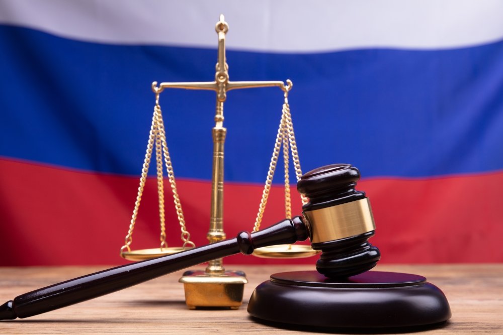 Judge Gavel And Justice Scale On Desk In Front Of Russian Flag