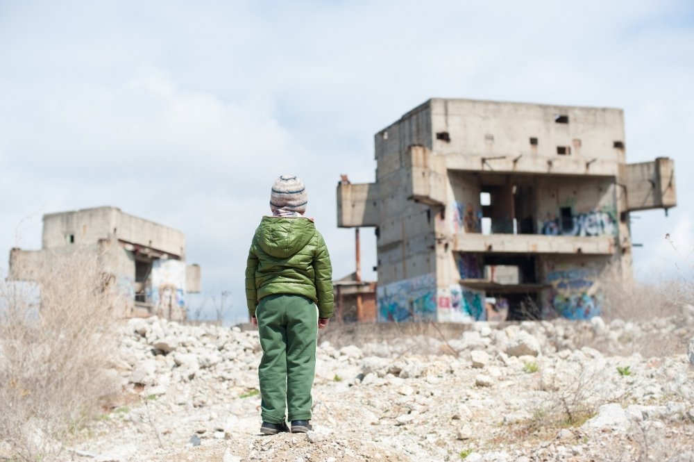 image of young boy looking over a bombed-out building 