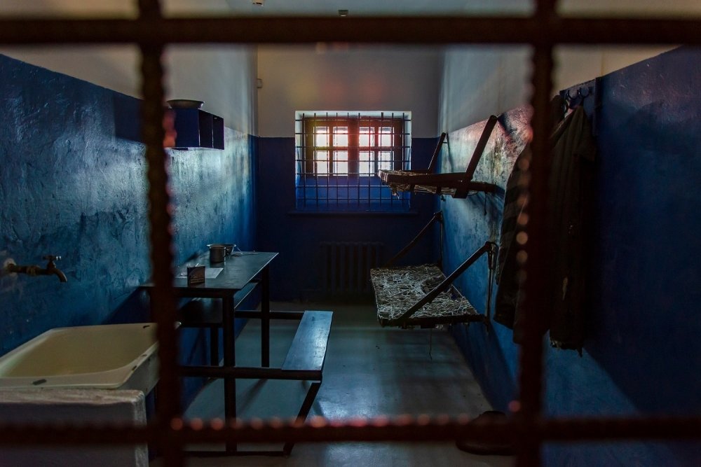 Empty prison cell in Russia. Two beds, a table, a washstand and a toilet are behind bars.
