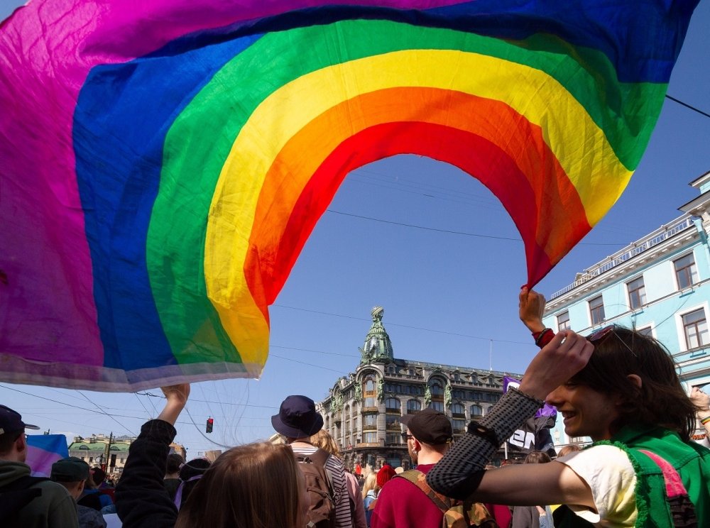 Person waving a pride flag on a busy street