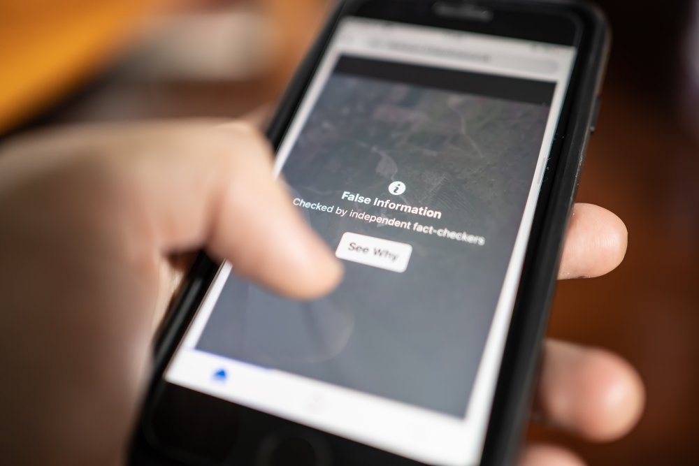 A phone displays a warning about false information.