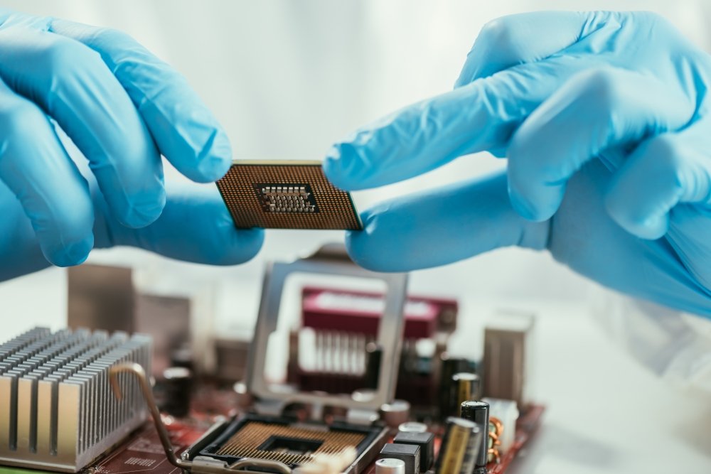 partial view of engineer holding microchip near computer motherboard