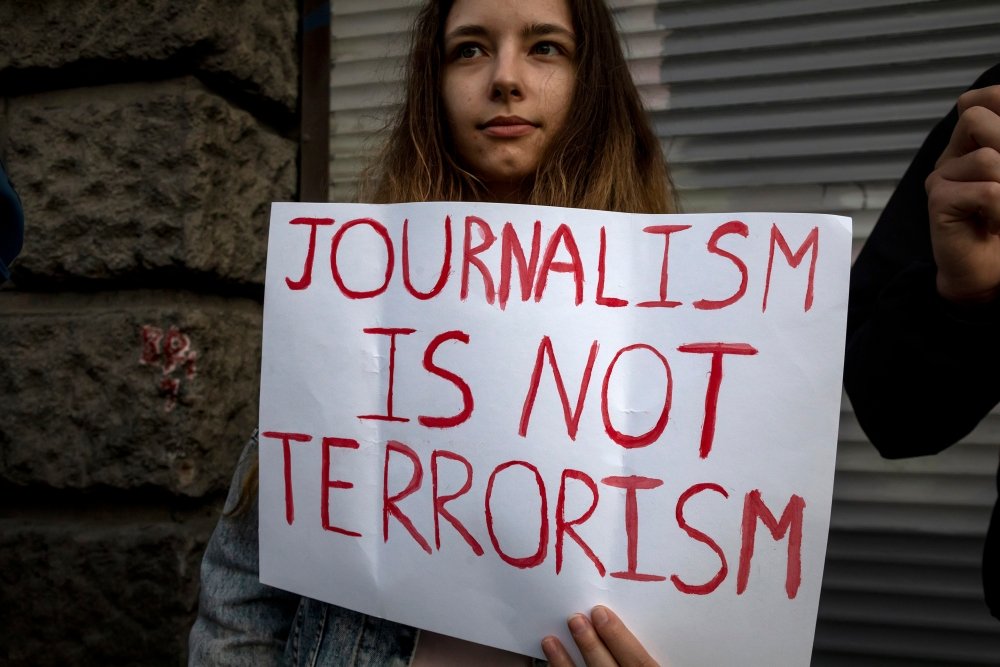  A woman holds a banner with the inscription "Journalism is not terrorism" in support of independent journalists