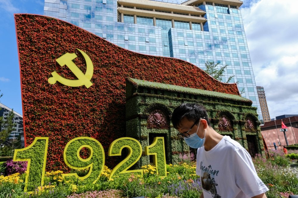 Beijing China - July 3 2021: A man walks in front of a display marking the centennial anniversary of the Communist Party of China (CPC) 