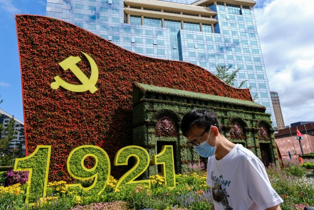 Beijing China - July 3 2021: A man walks in front of a display marking the centennial anniversary of the Communist Party of China (CPC)