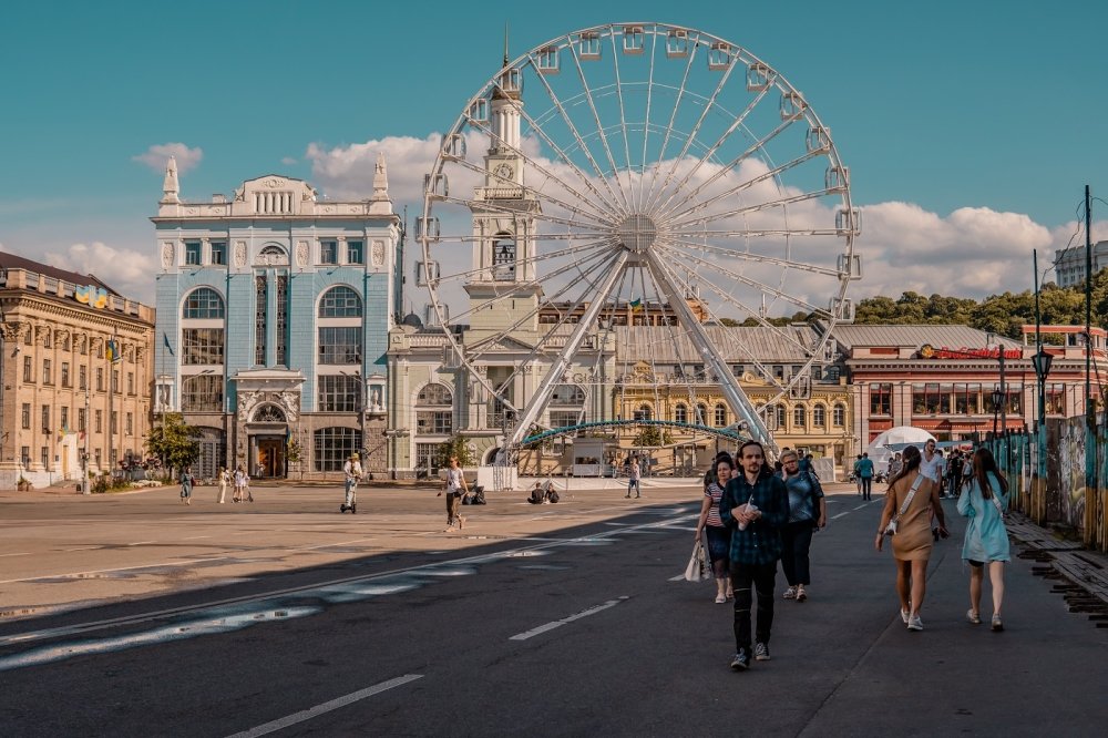 Podil, Kyiv, Ukraine - June 16, 2021 - street shot of people on the main square of the Podil neighborhood with ferris wheel and traditional architecture
