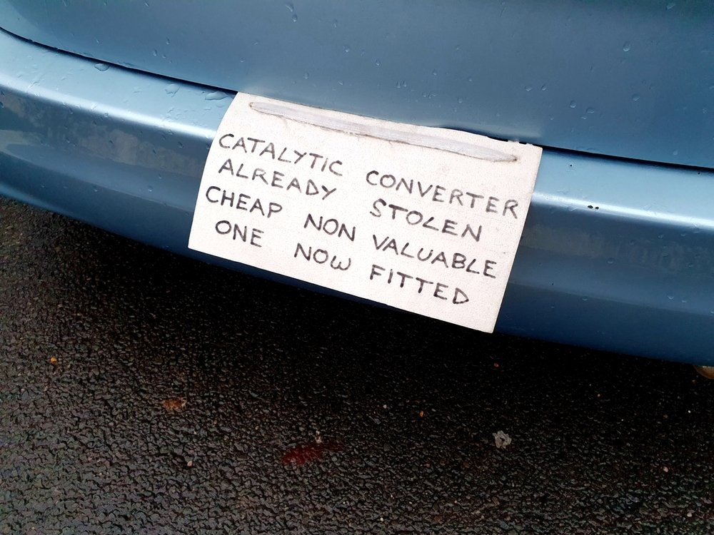 Sign on vehicle warning potential criminals that the catalytic converter has already been stolen and a cheaper part substituted