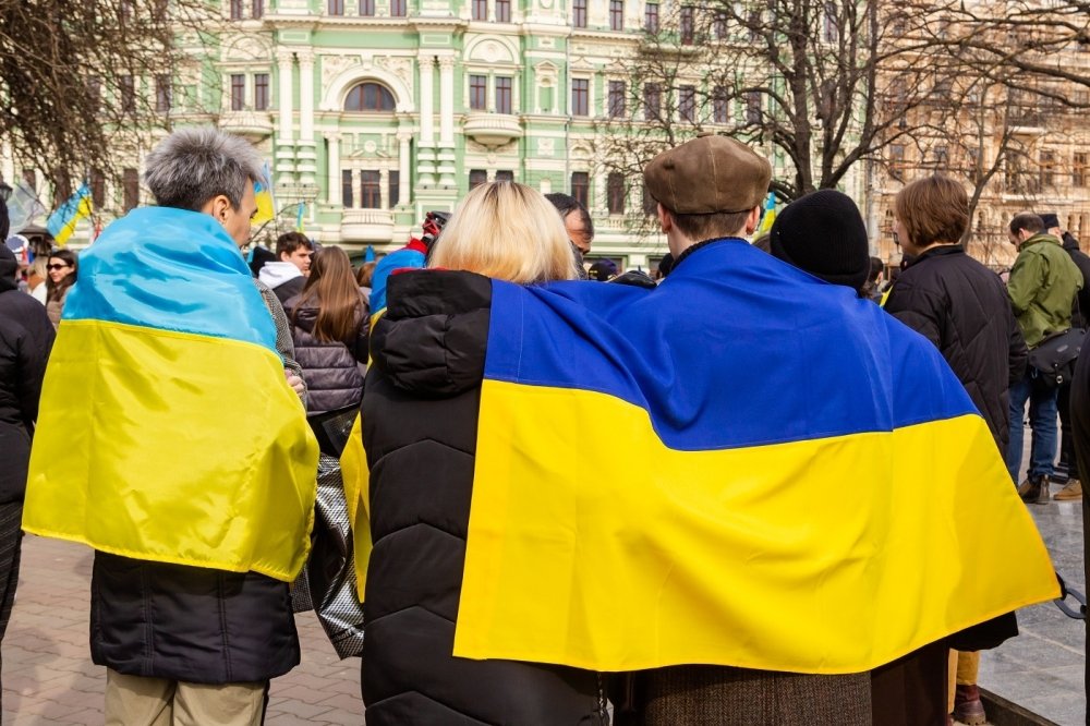 Ukrainian flag draped over peoples' backs