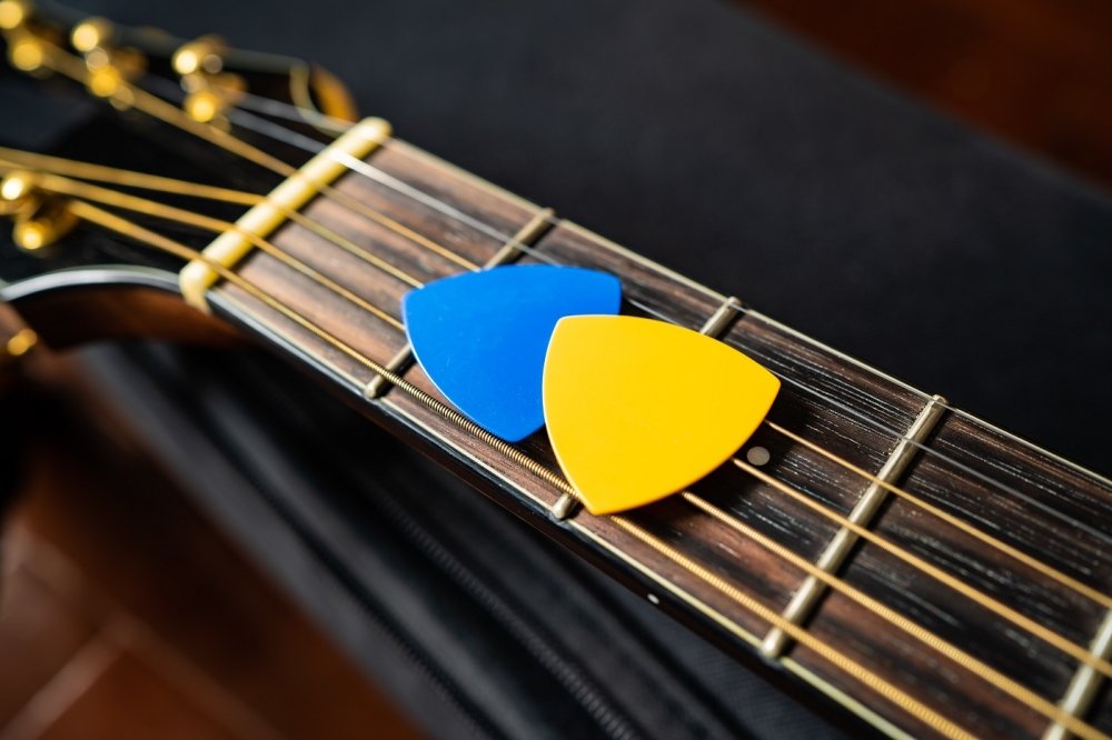 Blue and yellow guitar picks on an acoustic guitar