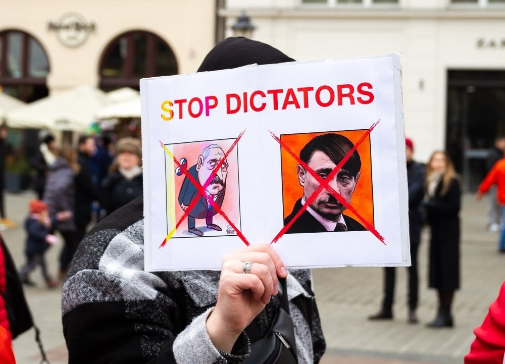 Protest poster with phrase "STOP DICTATORS" and satirical images of Putin and Lukashenko