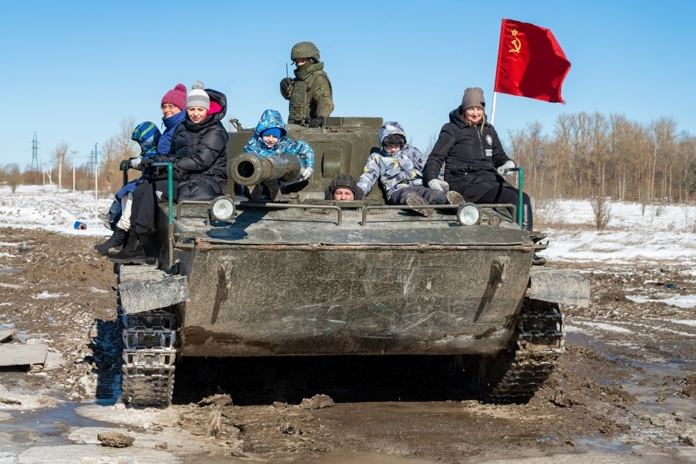 Visitors with children ride in the Soviet amphibious tank of PT-76 on a sunny March day.